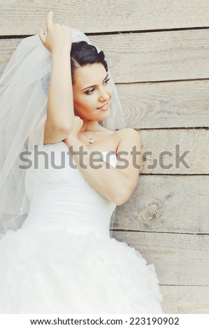 Cute brunette caucasian bride in white dress. Long veil.