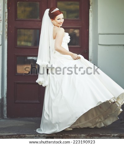 Beautiful caucasian lovely red hair bride in white dress. Long veil.