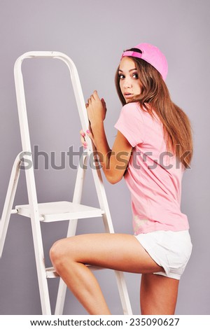 Teen posing on double ladder, studio shot.