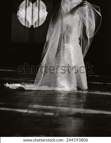 Beautiful bride playing with long veil, wedding picture in black and white.