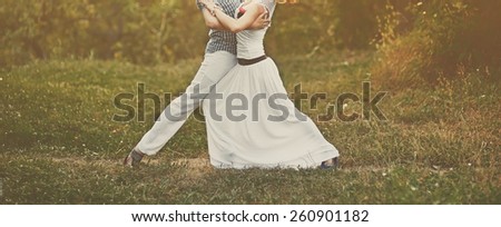 Young couple of professional dancers posing in garden.