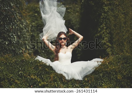 Stylish bride with flying veil. Young happy  fiancee in park.