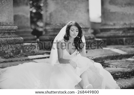 Young bride  posing  against an old church. Wedding picture in black and white.