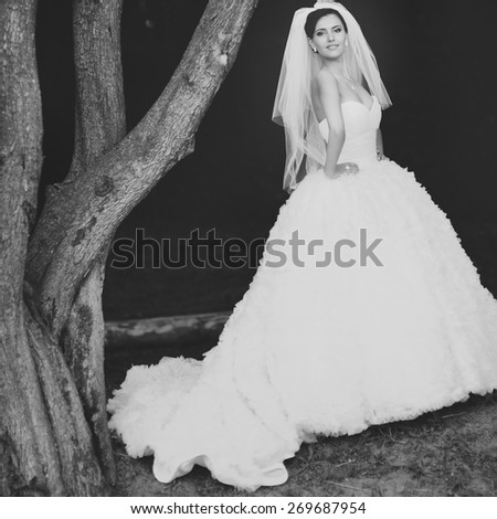 Happy beautiful brunette bride in white wedding dress with hairstyle posing in summer garden.
