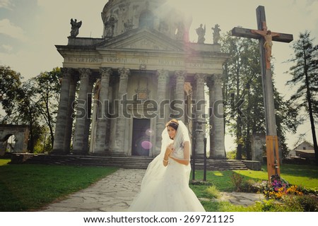 Beautiful young bride wearing wedding dress and posing next to old church.
