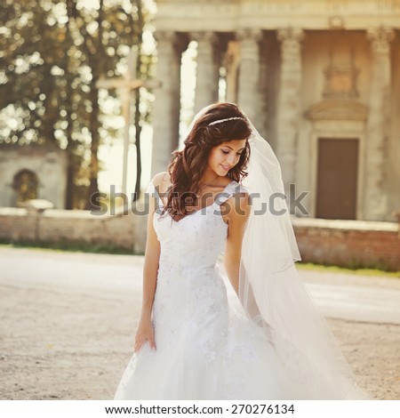 Beautiful young bride posing against old church.