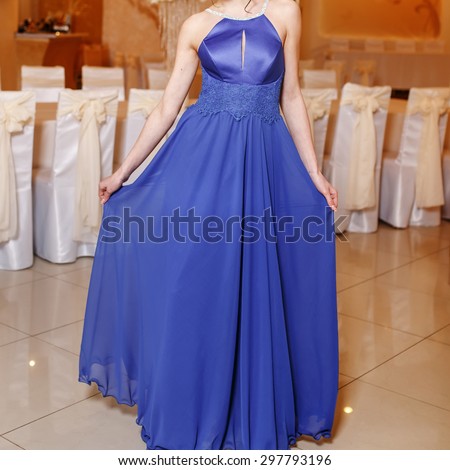 Interior portrait of young brunette woman wearing blue prom dress.  Graduate student.