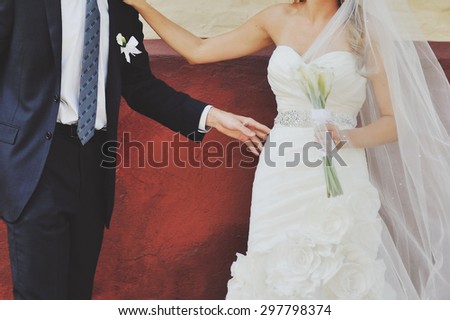 Groom and bride next to red wall. Wedding  couple together.
