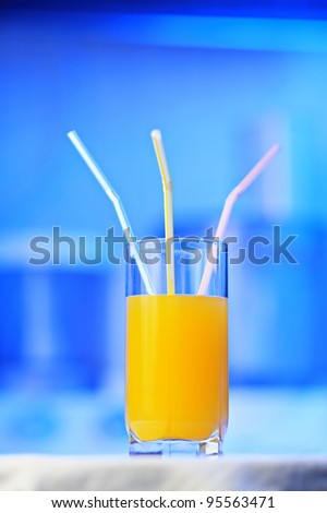 Glass of orange juice with three straws, shallow DOF focus on a middle straw