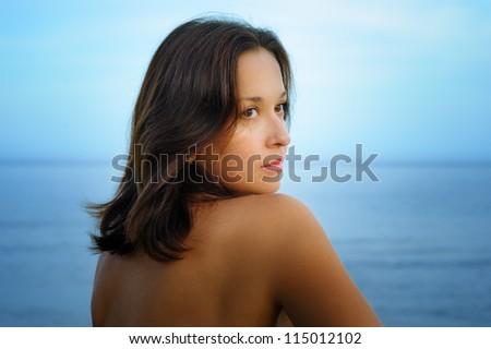 Young woman with bronzed skin  posing on beach
