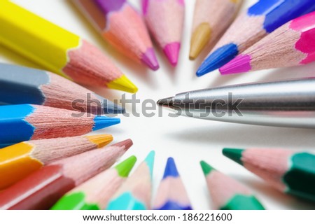 Metal pen among color pencils, on light background