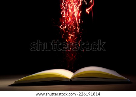 Open book with magic lights on dark background