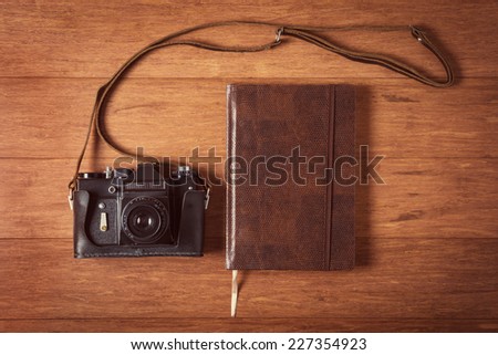 Vintage camera and diary on wooden table. Instagram style toned photo.