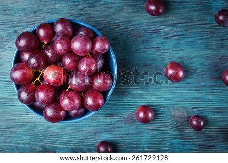 Top view of grapes with water drops in blue plate on wooden table