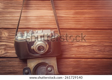 Retro camera over old wooden background. Vintage filtered effect.