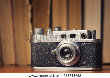 Vintage 35mm film camera over old books defocused background