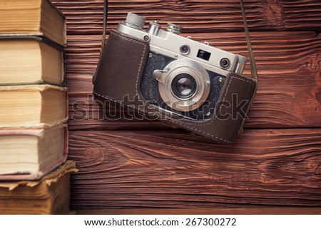 Vintage 35mm Film Camera and Stack of Books Over Wooden  Background