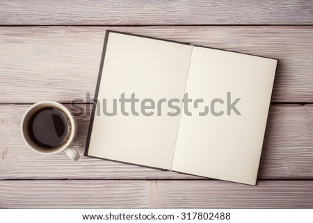 Open notebook with cup of coffee on wooden desk