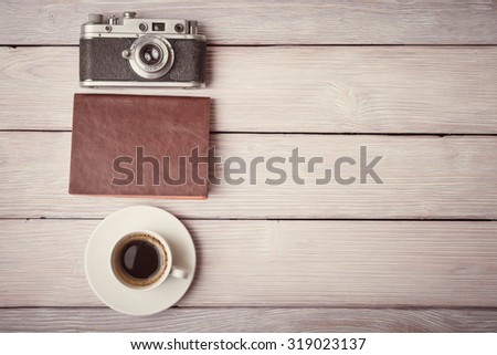 Retro camera, notebook and cup of coffee on wooden desk