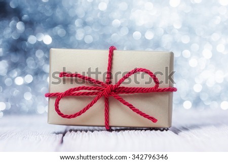 Gift box with red cord over abstract defocused lights