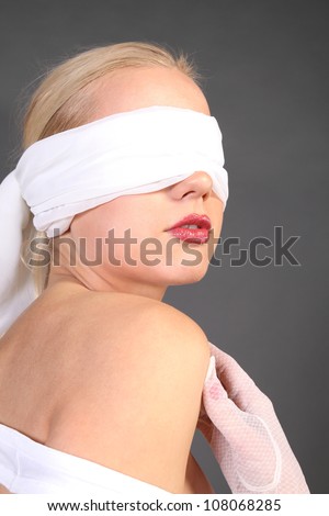 Girl tied up blind eyes to see, with red lips wearing gloves looks toward the text