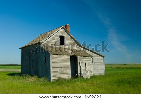 abandoned farm house in field against deep blue sky showing how people lived in the past