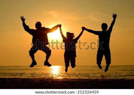 Silhouette Group of happy people man and woman jumping on the beach