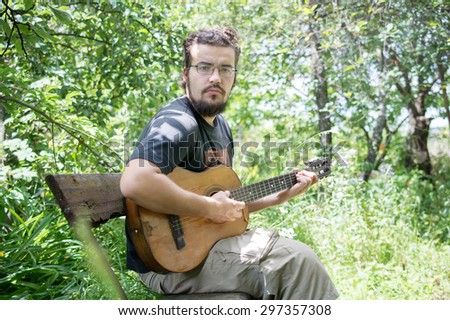young guy playing guitar in the garden