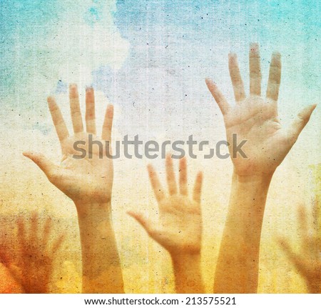 Raising hands against vintage blue sky background. Filtered image.