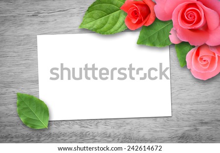 Pink roses with empty white card on old wooden table. Romantic floral frame background. Valentines day concept