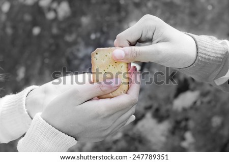 Sharing food. Women giving a cracker to a small child. Charity concept.