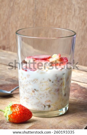 Crunchy musli (whole grain oats) served with fresh strawberries and low fat yogurt in a glass bowl - healthy breakfast.