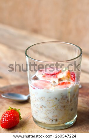 Crunchy musli (whole grain oats) served with fresh strawberries and low fat yogurt in a glass bowl - healthy breakfast.