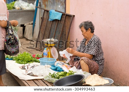 Nongkhai, Thailand - June 26: Unidentified shop seller selling her goods to his customer at market on Phonphisia in Nongkhai, Thailand on June 26, 2015.