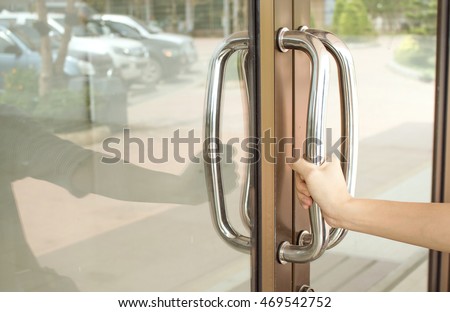 Close-up of hand open Aluminum glass door holding handle.