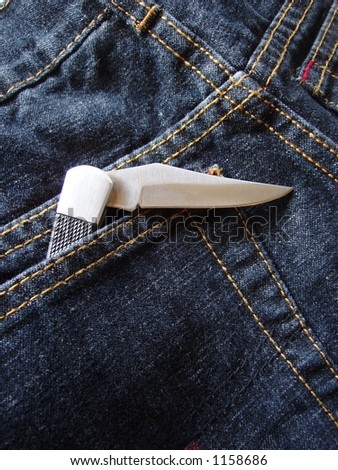open pocket knife in back pocket of blue jeans