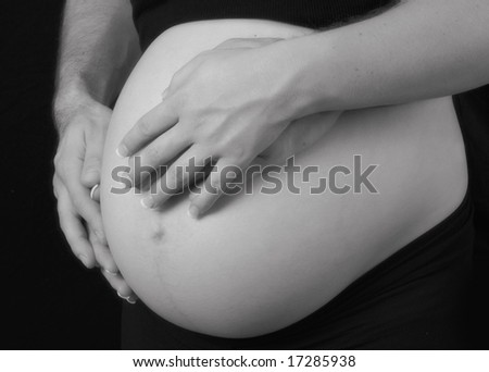 mothers and fathers loving hands wrapped around pregnant woman belly