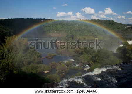 a spectacular rainbow over  the iguazu falls, one of the seven natural wonders of the world, between Argentina and Brazil