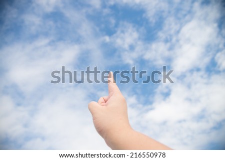 Human finger points to the sky with clouds