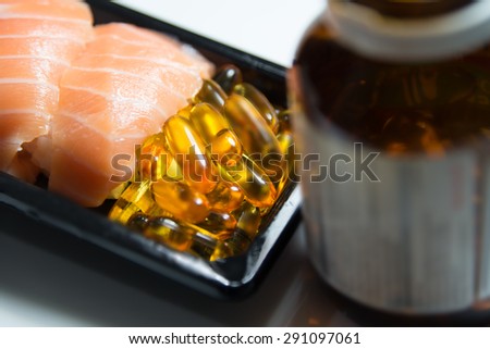 Sushi served with piles of fish oil capsules food supplement near brown bottle isolated on white background