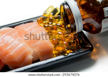 Salmon sushi served with fish oil pills poured from brown bottle isolated on white background