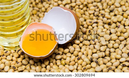 Cracked egg and soy bean oil bottle on soy beans background