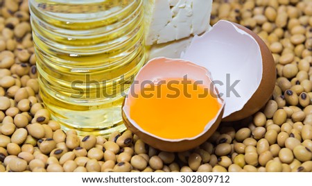 Vegetarian product : soy bean oil bottle, cracked hen egg  and tofu on soy beans background