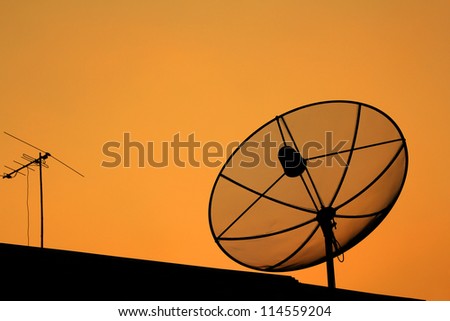 Black antenna communication satellite dish in sunset sky