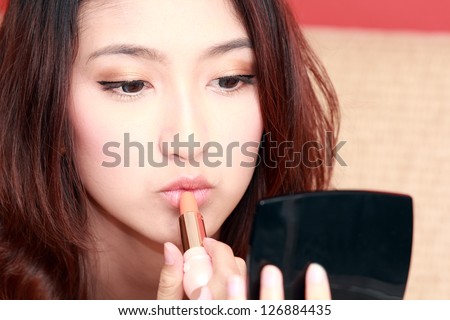 Young asian cute woman with lipstick brush for makeup. Lips zone