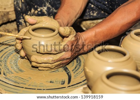 Hands of a potter with creating an earthen jar on the circle