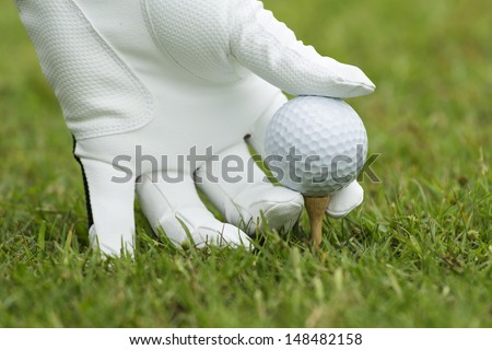 Hand and golf ball on green grass outdoor close up