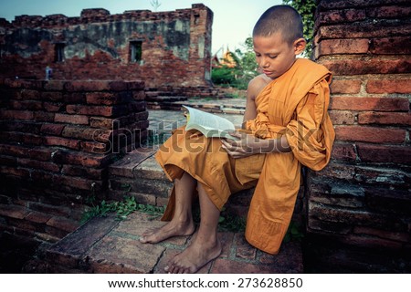 Young Novice reading book at Ayutthaya historical park  in Thailand