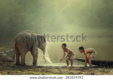 Two boys are playing splashing water with baby elephant at pond