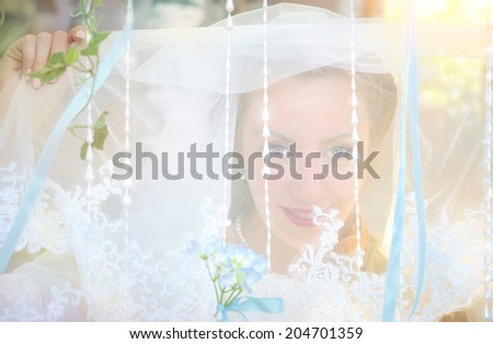 The bride\'s face is hidden wedding veil. Portrait of a beautiful smiling blonde bride